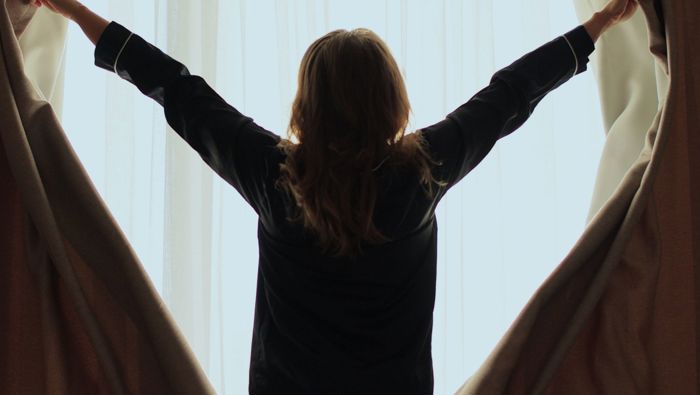 Woman opening curtains