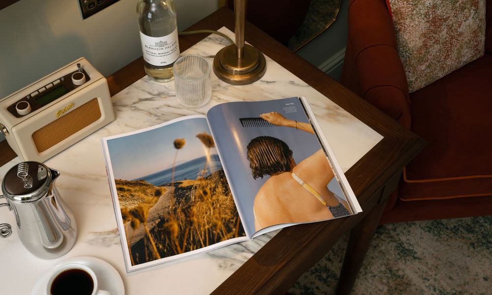 open magazine on table with coffee pot, cup of coffee and radio