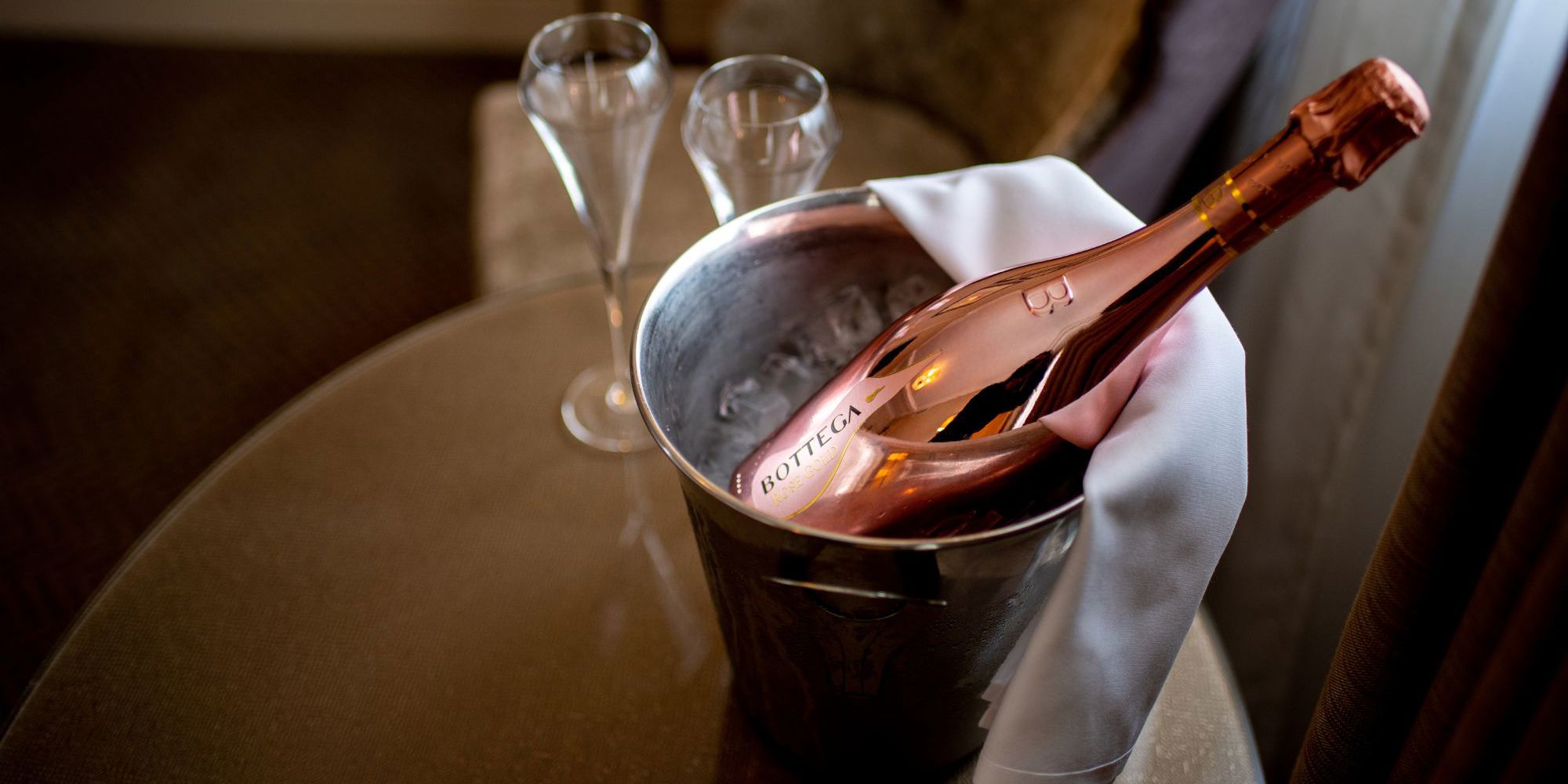 Bottle of sparkling wine with glasses in hotel room