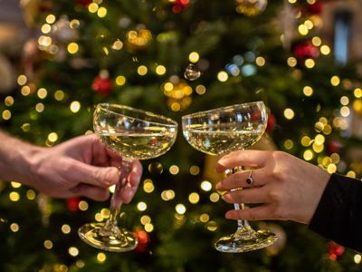 Glasses clinking in front of Christmas tree