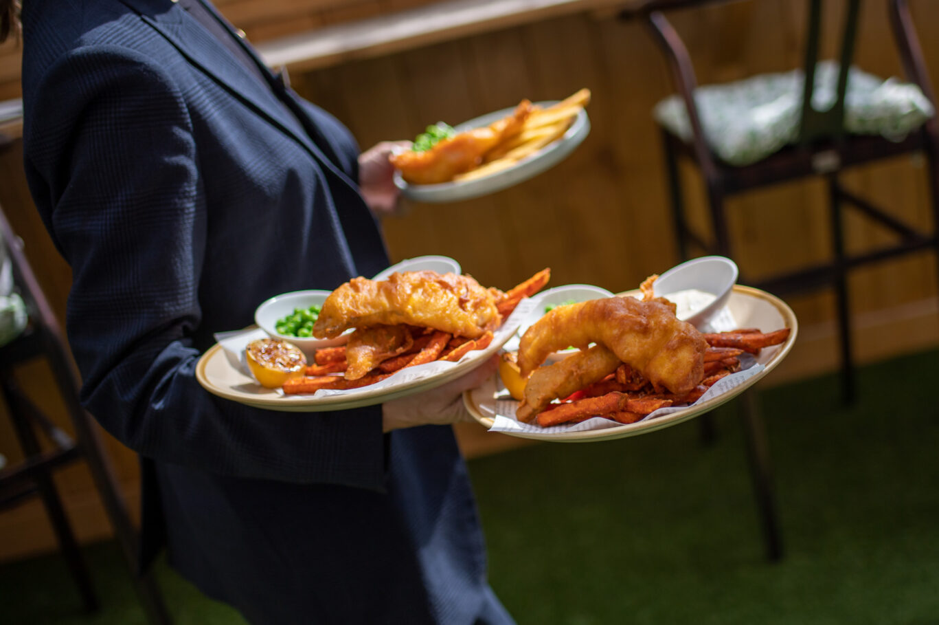 Waiter delivering plates of food on outside terrace