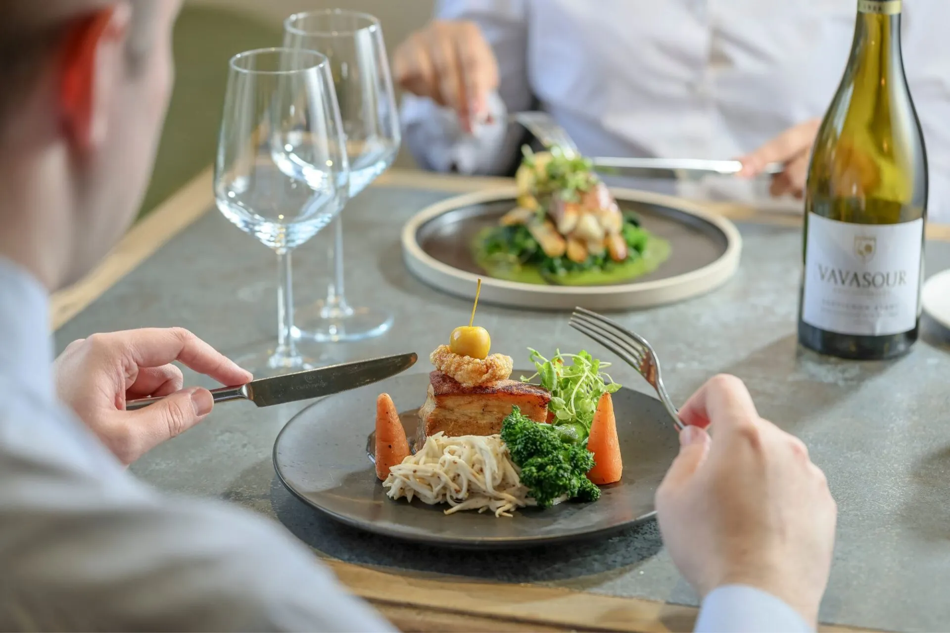 Couple eating crispy pork belly and monkfish tail wrapped with Serrano ham