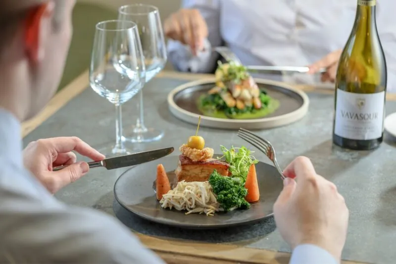 Couple eating crispy pork belly and monkfish tail wrapped with Serrano ham