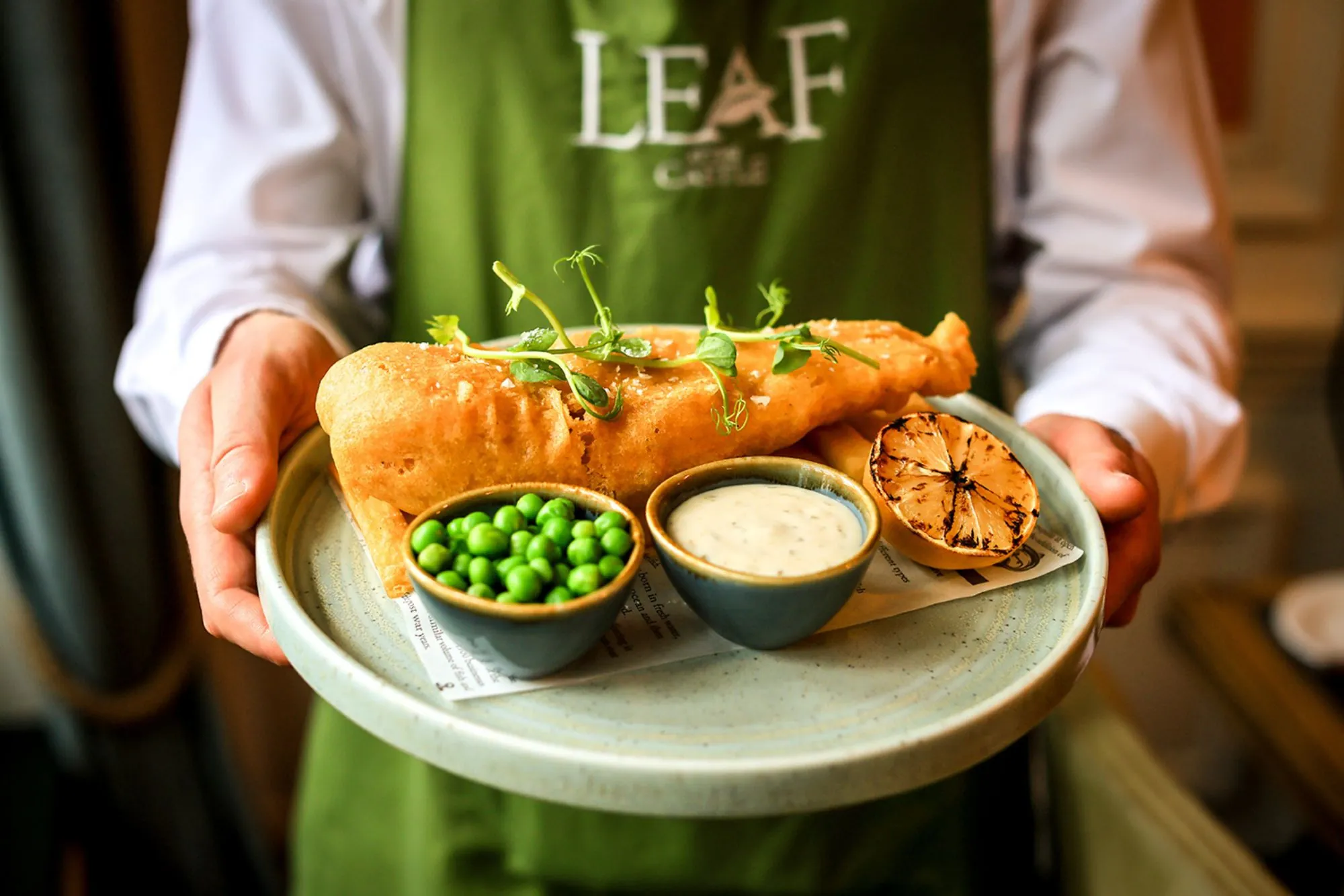 The Castle Hotel Windsor waiter holding battered hake and chips